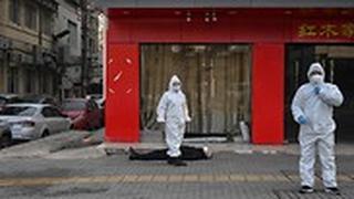 אנשי צוות רפואי בודקים אדם שהתמוטט ברחובות העיר ווהאן בסין