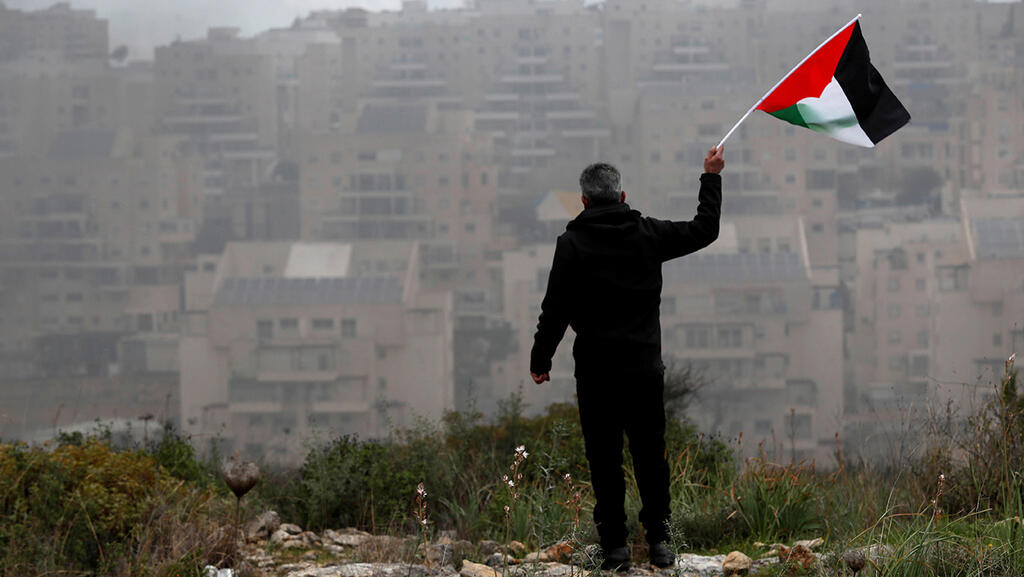 פלסטיני מנופף ב דגל פלסטין מול מודיעין עילית