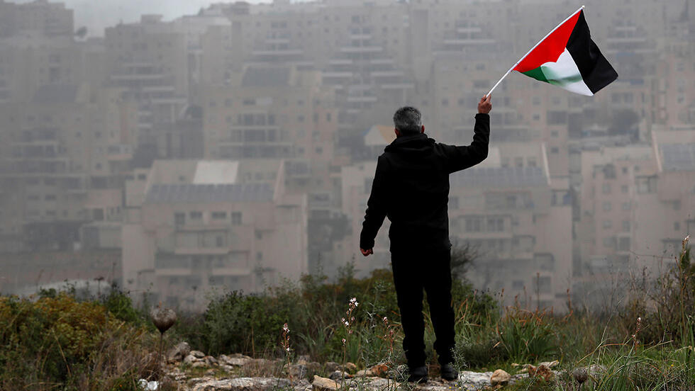 פלסטיני מנופף ב דגל פלסטין מול מודיעין עילית
