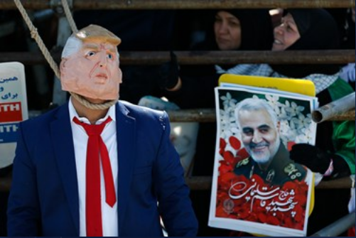 A man dressed as an effegy of U.S. President Trump next to a picture of Qassem Soleimani 