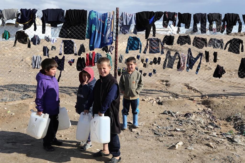 Children hold onto water containers in al-Hol camp 