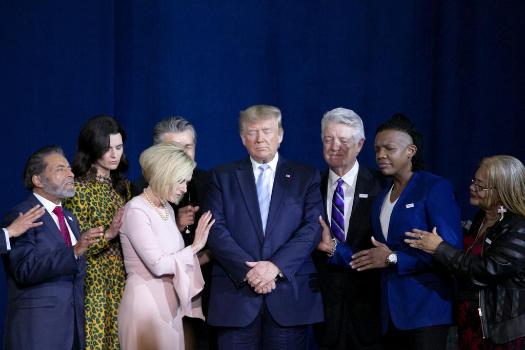 Donald Trump praying in a rally for evangelical voters 