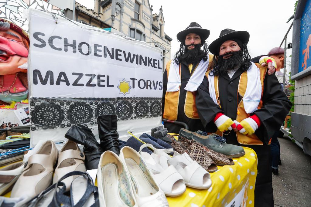 People dressed as caricatures of Orthodox Jews pretend to sell shoes at the parade in Aalst, Feb. 23 2020 