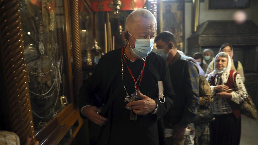 A priest and visitors wear masks at the Church of the Nativity in Bethlehem after a suspected coronavirus outbreak in the city, March 5, 2020 