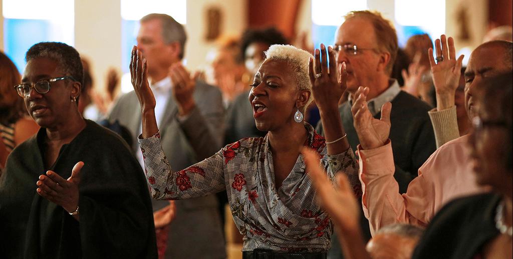 מתפללים מרימים ידיים במקום להחזיק ידיים בגלל נגיף קורונה כנסייה אטלנטה ג'ורג'יה ארה"ב