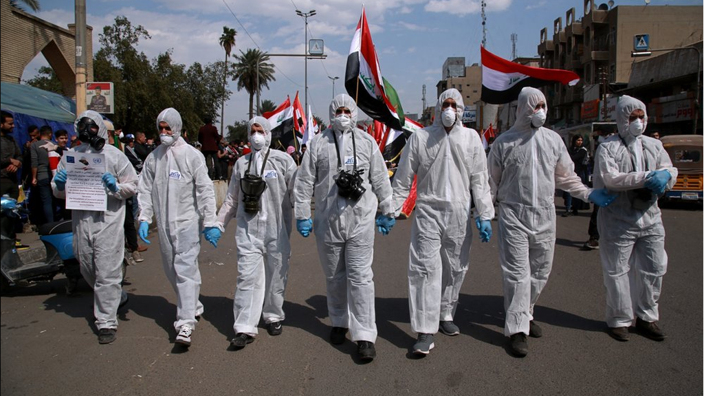 Anti-government protesters wear hazmat-like suits and gas masks during a rally in Baghdad 