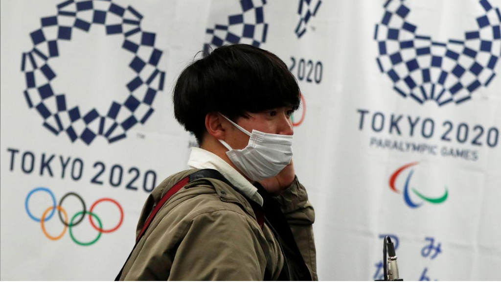 A man in Tokyo wearing a protective mask, walking in front of the IOC offices 
