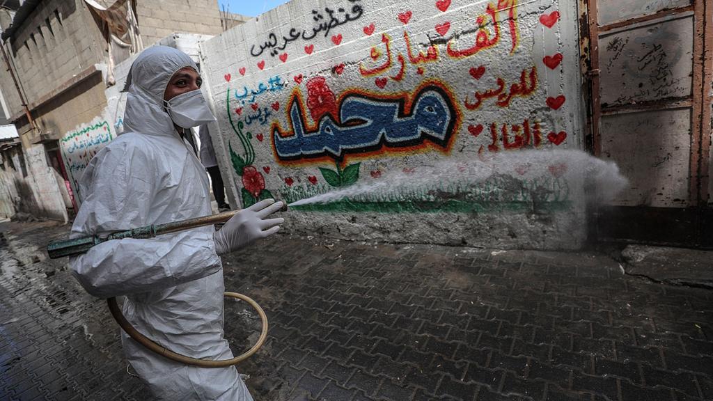 A medical worker in Gaza disinfecting a street in Gaza City 