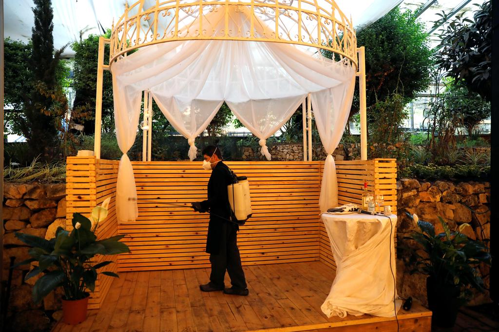 An employee sanitises the chuppah before Roni Ben-Ari and Yonatan   Meushar get married at Ein Hemed Forest Wedding Venue, March 18, 2020 