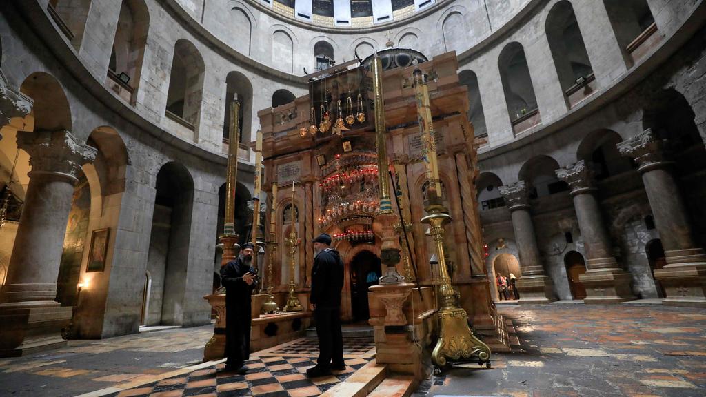 A Greek Orthodox priest and a caretaker stand in front the   deserted Edicule in the Church of the Holy Sepulchre in   the Old City of Jerusalem, March 15, 2020 
