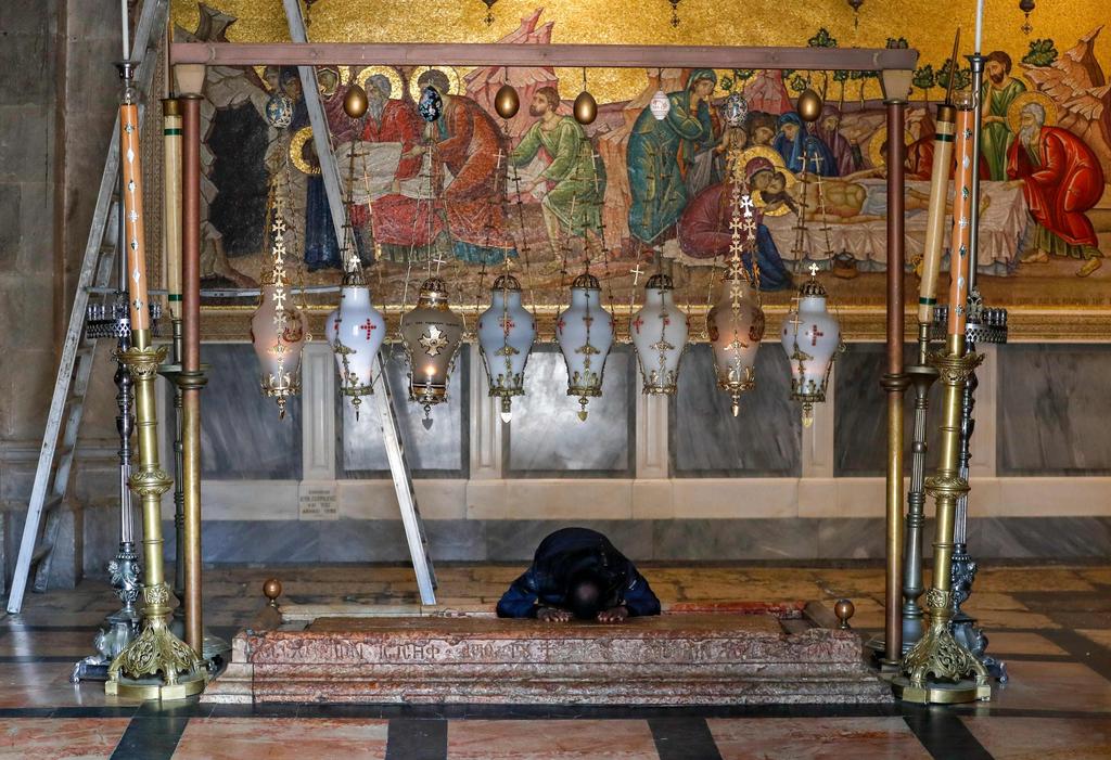 A lone worshipper prays over the Stone of Anointing at the Church   of the Holy Sepulchre in the Old City of Jerusalem, March 22, 2020 