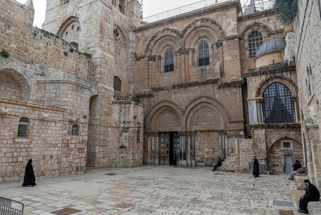 Priests walk in the often bustling plaza in front of the Church of the Holy Sepulchre in the Old City of Jerusalem, March 22, 2020 