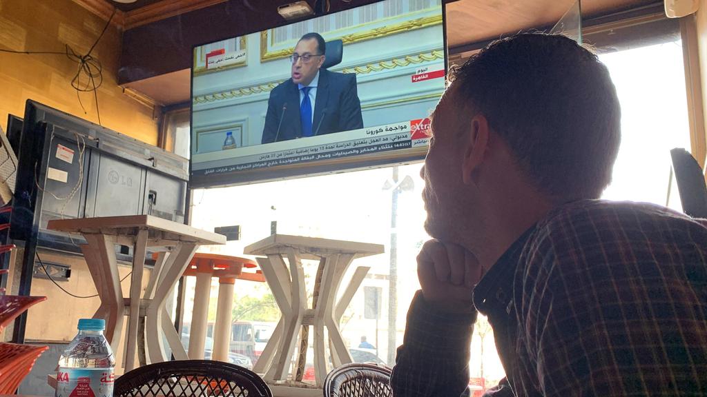 Egyptian man attentive to his PM announcing measures to counter coronavirus