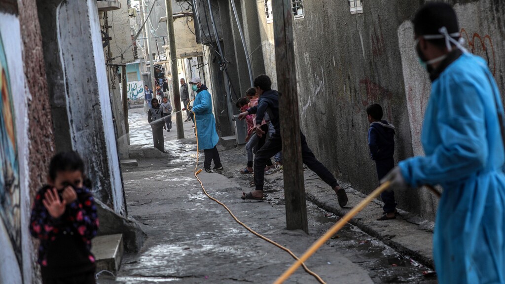 Palestinians spray disinfectant as a precaution against the spread of the Covid-19 coronavirus, in the streets of Al Nusairat refugee camp, central Gaza Strip 
