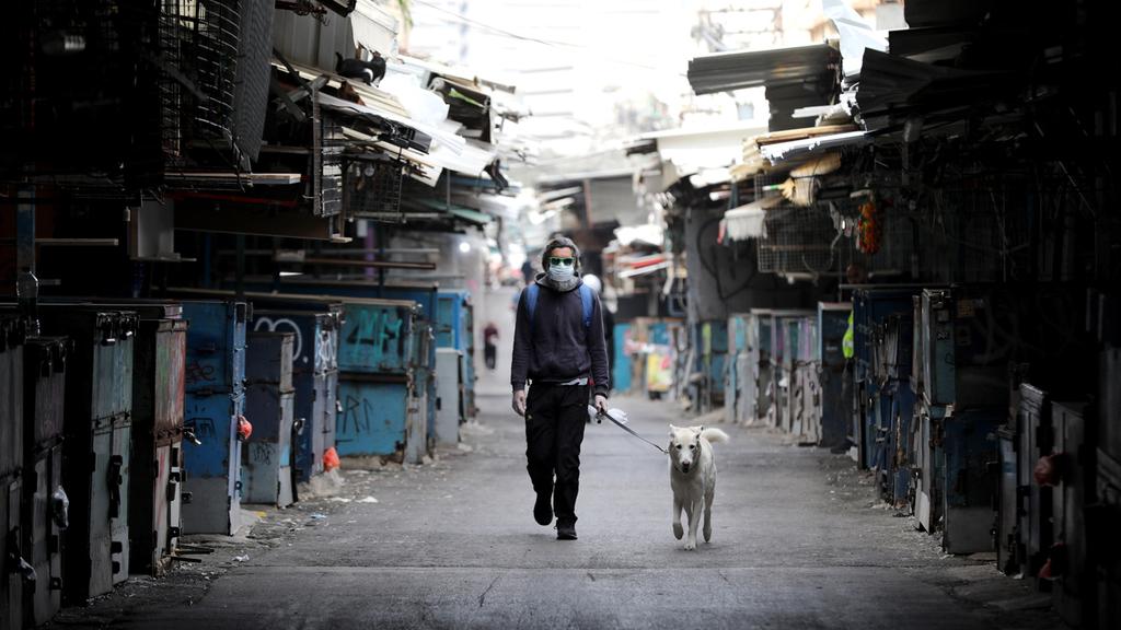  A man walks his dog past the shuttered stalls of the normally bustling Carmel Market in Tel Aviv 