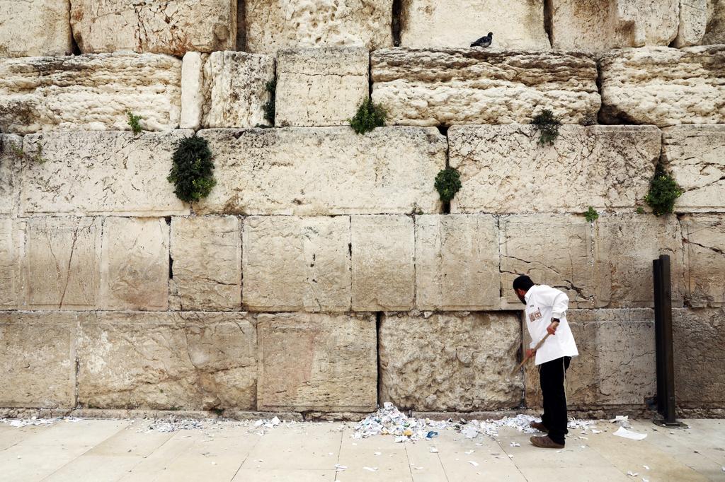 A man clears notes placed in the cracks of the Western Wall to   create space for new notes ahead of Passover, March 31, 2020 