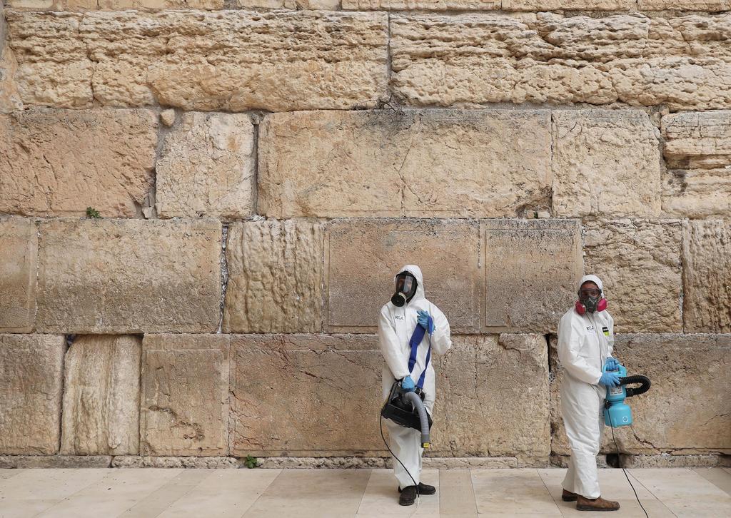 Workers wearing protective suits spray disinfectant at the Western   Wall plaza in the Old City of Jerusalem, March 31, 2020 