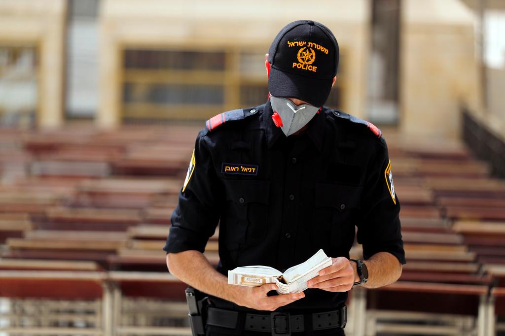 A policeman wearing a mask prays besides the Western Wall in Jerusalem, March 31, 2020 