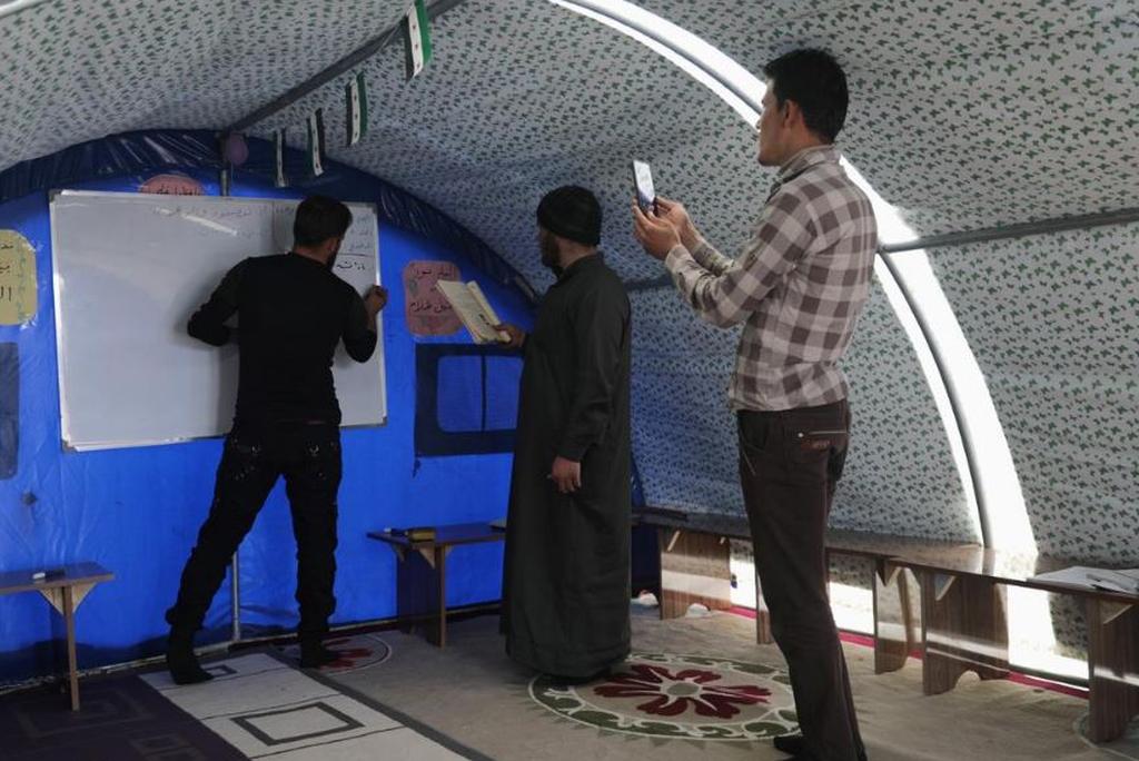 Ahmed Hadaja, a 21-year-old medic and volunteer Arabic teacher, records with other teachers a video lesson to be sent for students, after their tented school was shut due to the threat of coronavirus disease (COVID-19) in Atmeh camp, near the Turkish border