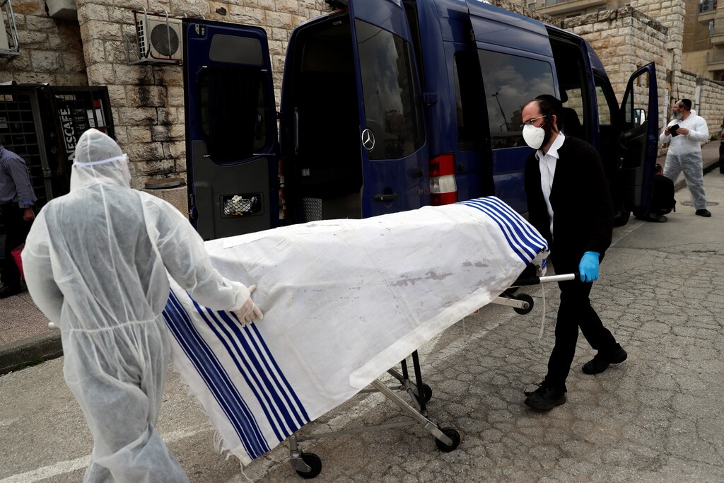 Workers of Jewish Burial Society wear protective gear as they carry the body of a victim of coronavirus disease (COVID-19) to be buried in Jerusalem April 2, 2020 