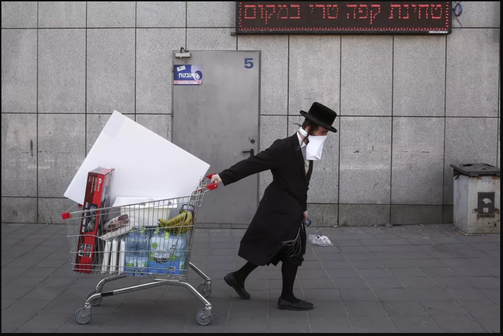 An ultra-Orthodox Jew wears an improvised protective face mask as he pulls a supermarket cart in Bnei Brak 