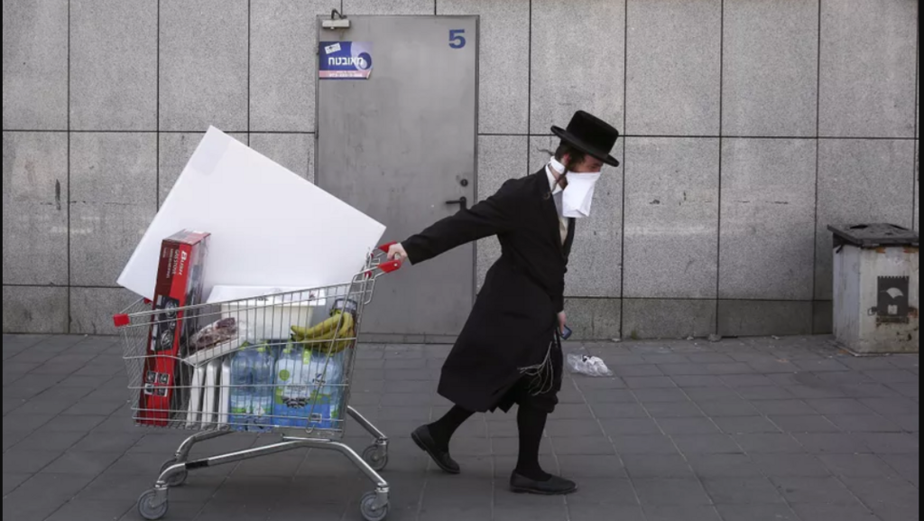An ultra-Orthodox Jew wears an improvised protective face mask as he pulls a supermarket cart in Bnei Brak 