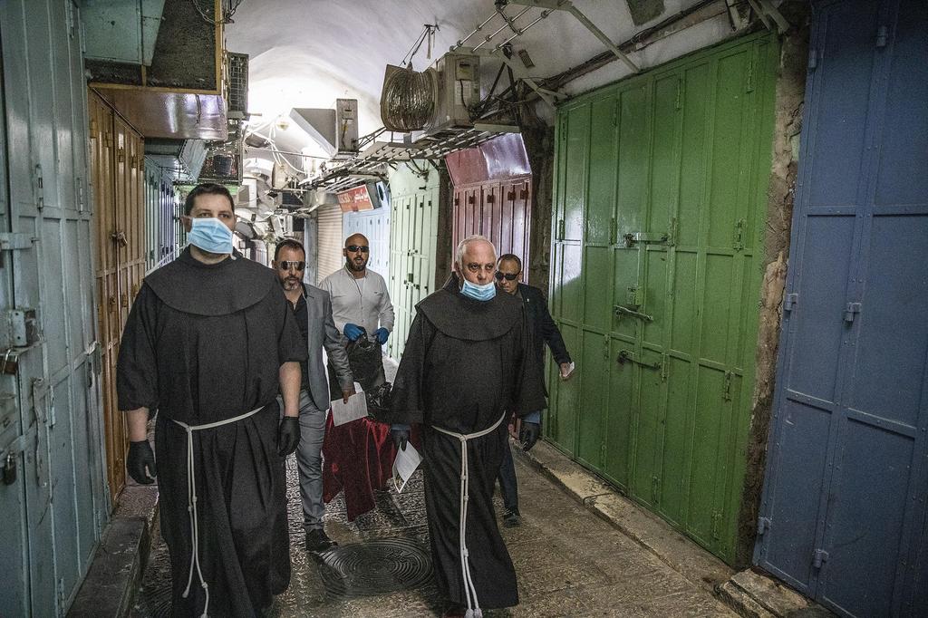 Monks walk in Jerusalem's Old City's street during a small Palm Sunday procession going door to door 