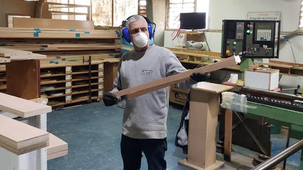 A carpenter at Kibbutz Lavi wears protective gear as he makes synagogue furniture 