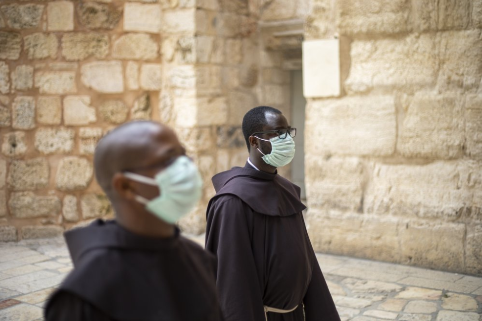 Priests wearing protective face masks wait to enter the Church of the Holy Sepulchre 
