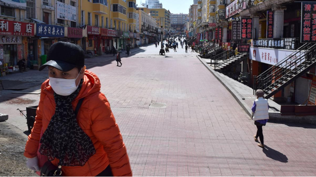 A resident wearing a face mask walks past a shopping street in Suifenhe, China 