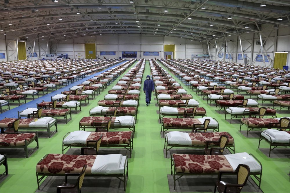 A member of the Iranian army walks past rows of beds at a temporary 2,000-bed hospital for coronavirus patients set up by the army at the international exhibition center in northern Tehran 