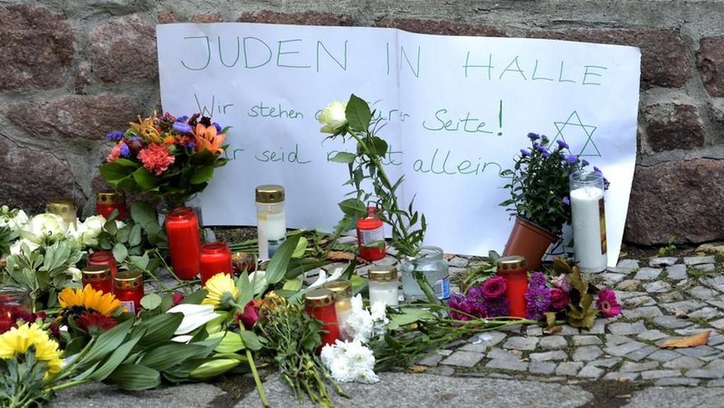 Candles and flowers placed in front of a synagogue in Halle, after a heavily armed assailant ranting about Jews tried to force his way into the synagogue in Germany; Sign reads, 'Jews in Halle - We stay next to you! You are not alone' 