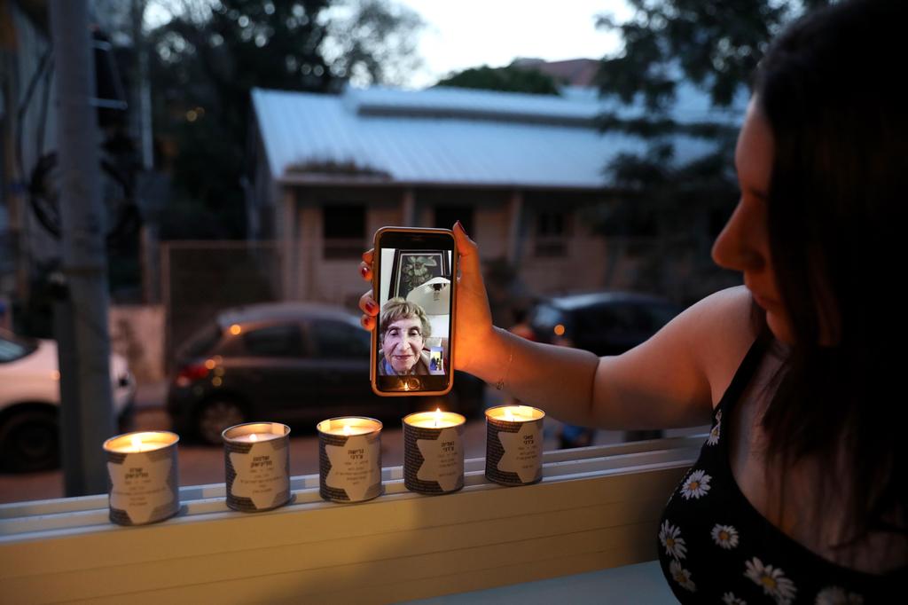 Family member of Holocaust survivor Sonia Perminger (on display), granddaughter Shani Maliniak lights memorial candles in her balcony of her apartment on the eve of Holocaust Remembrance Day 