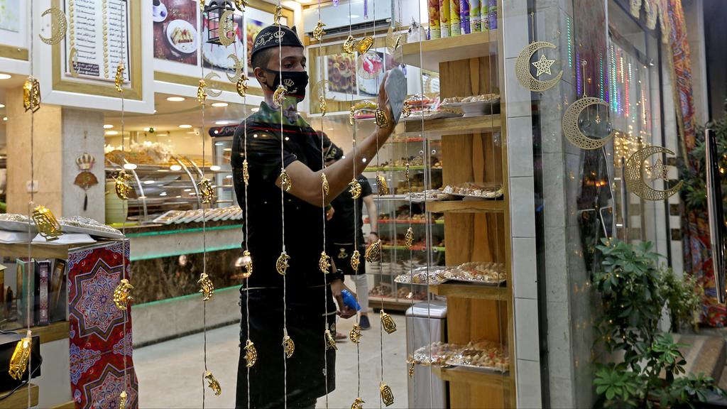 A Palestinian worker in southern Gaza cleans the window of a sweet shop ahead of Ramadan, amid concerns about the spread of coronavirus 