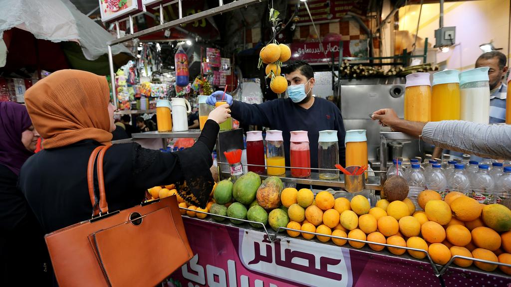 A Palestinian worker in the southern Gaza Strip sprays water outside shops decorated for Ramadan, amid concerns about the spread of coronavirus 