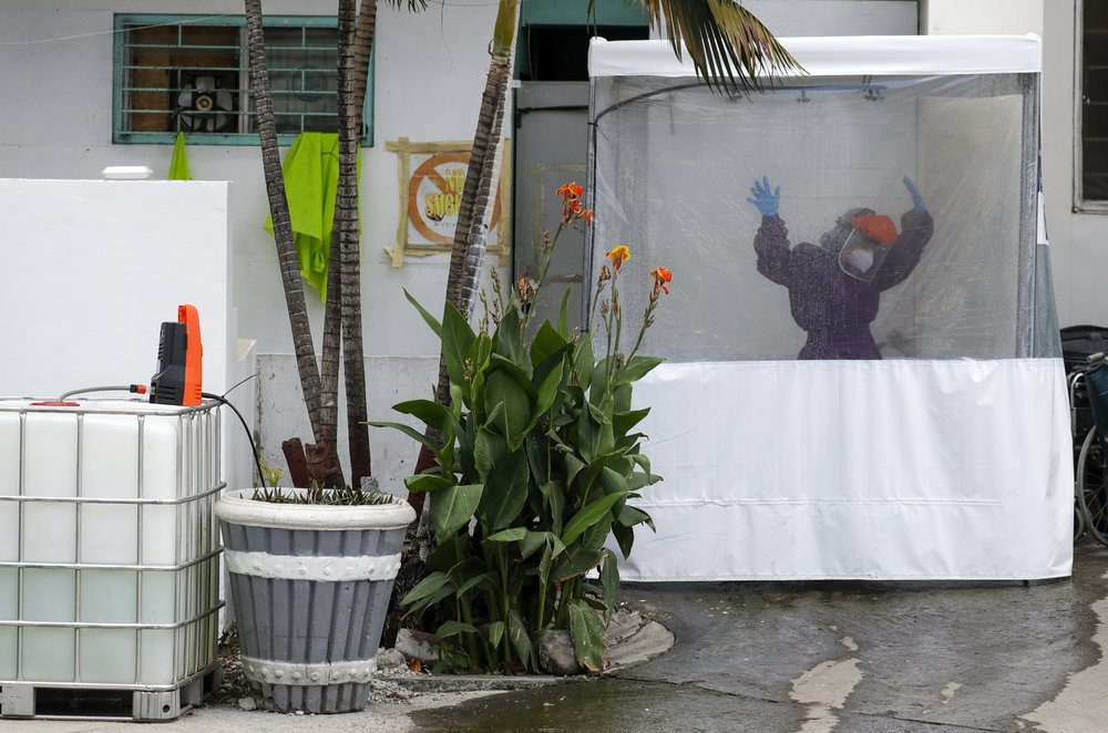 A health worker wearing a protective suit raises her hands as she disinfects inside a portable tent beside a street at the Gat Andres Bonifacio Memorial Medical Center during an enhanced community quarantine to prevent the spread of the new coronavirus in Manila, Philippines 