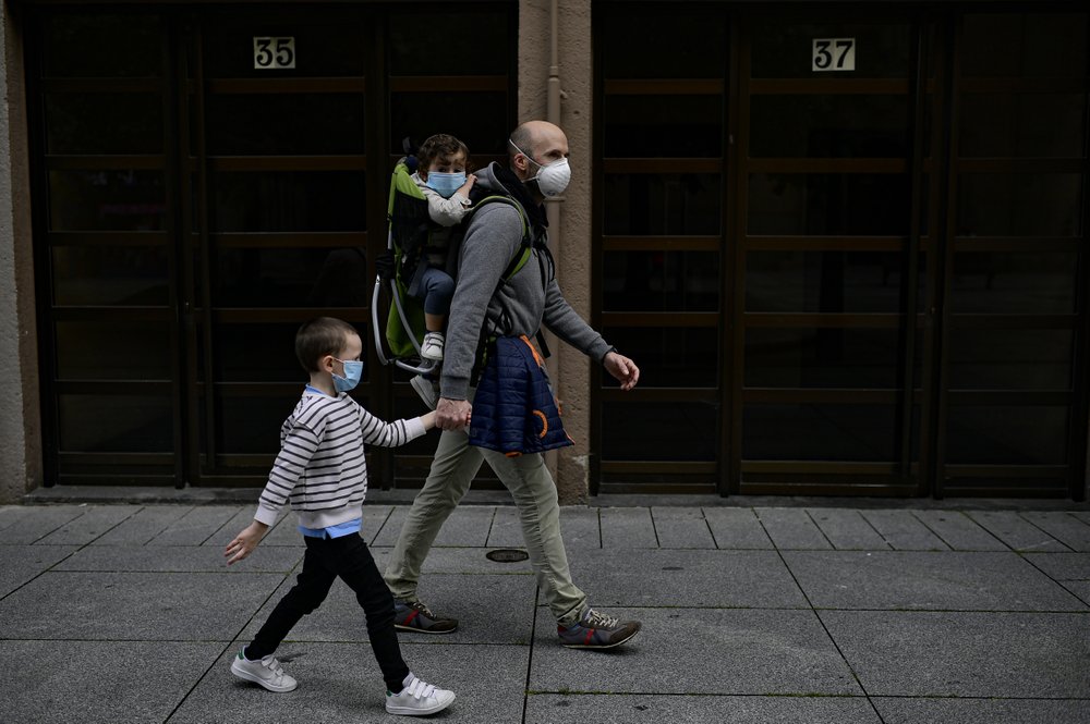 A father with his children wearing face mask to prevent the coronavirus go for a walk at Carlos III promenade, in Pamplona, northern Spain 