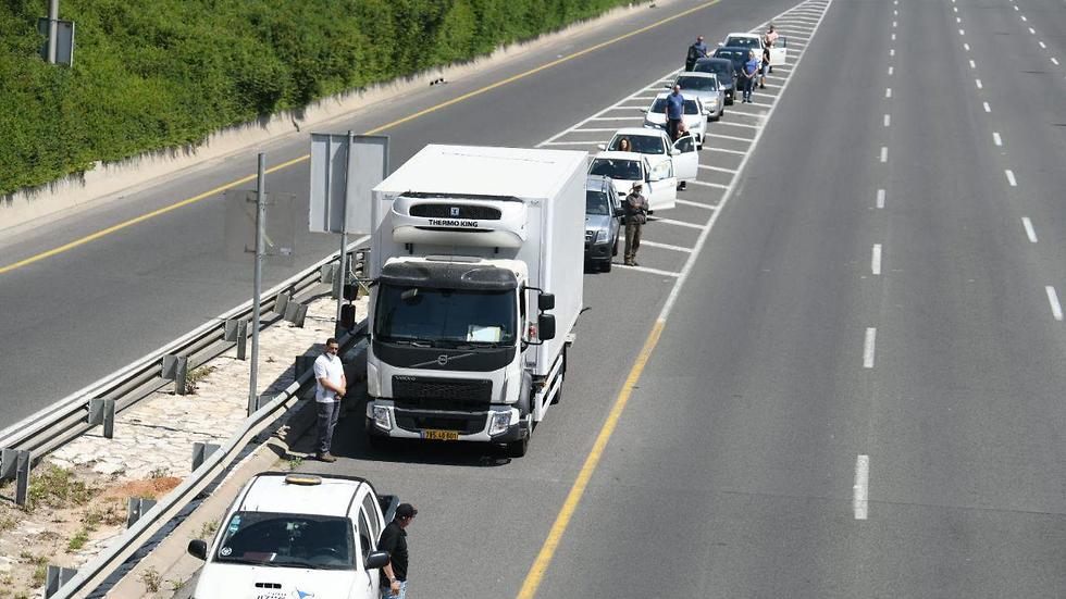 אנשים ורכבים עומדים בצפירת יום הזיכרון בנתיבי איילון