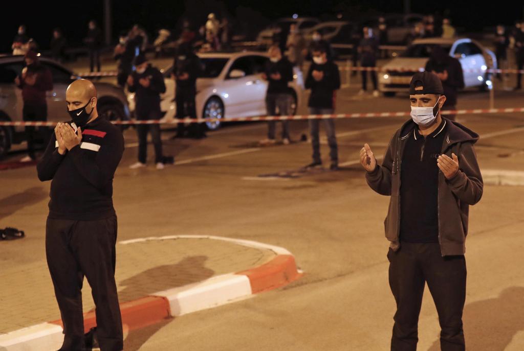 Palestinian and Arab Israeli men keep a 2-meter distance amid the COVID-19 pandemic, as they pray in a parking lot near the beach in Jaffa 