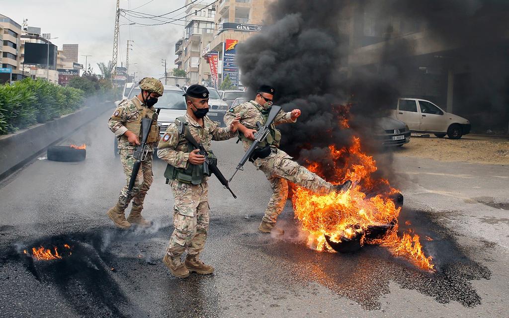 Lebanese soldiers remove burning tires placed by anti-government protesters to block a road in the town of Zouk Mosbeh, north of Beirut 