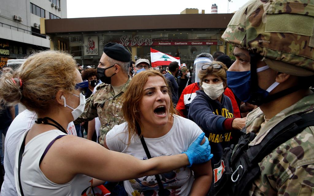 An anti-government protester scuffles with Lebanese army soldiers in the town of Zouk Mosbeh, north of Beirut 