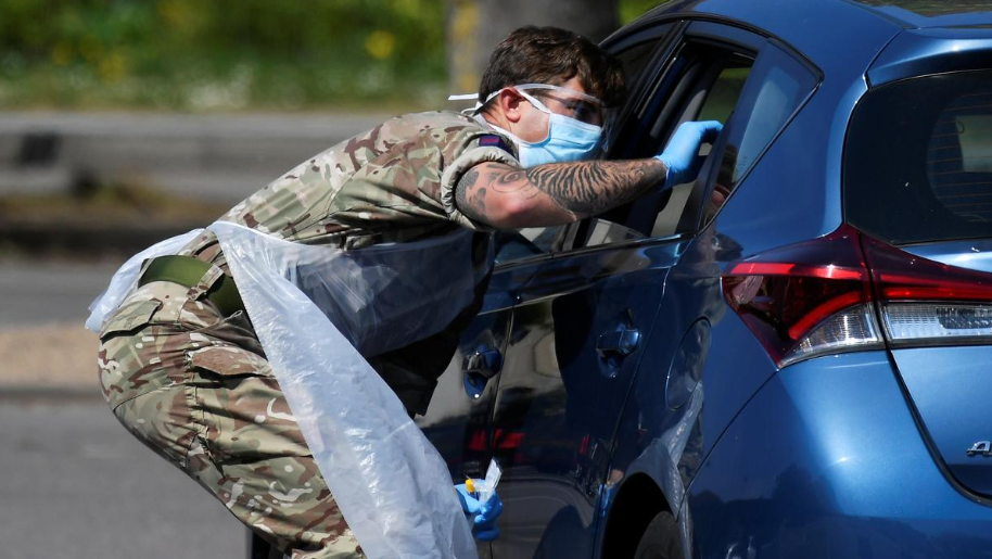 A member of the military tests a person at a coronavirus test centre in the car park of Chessington World of Adventures, Chessington, Britain 