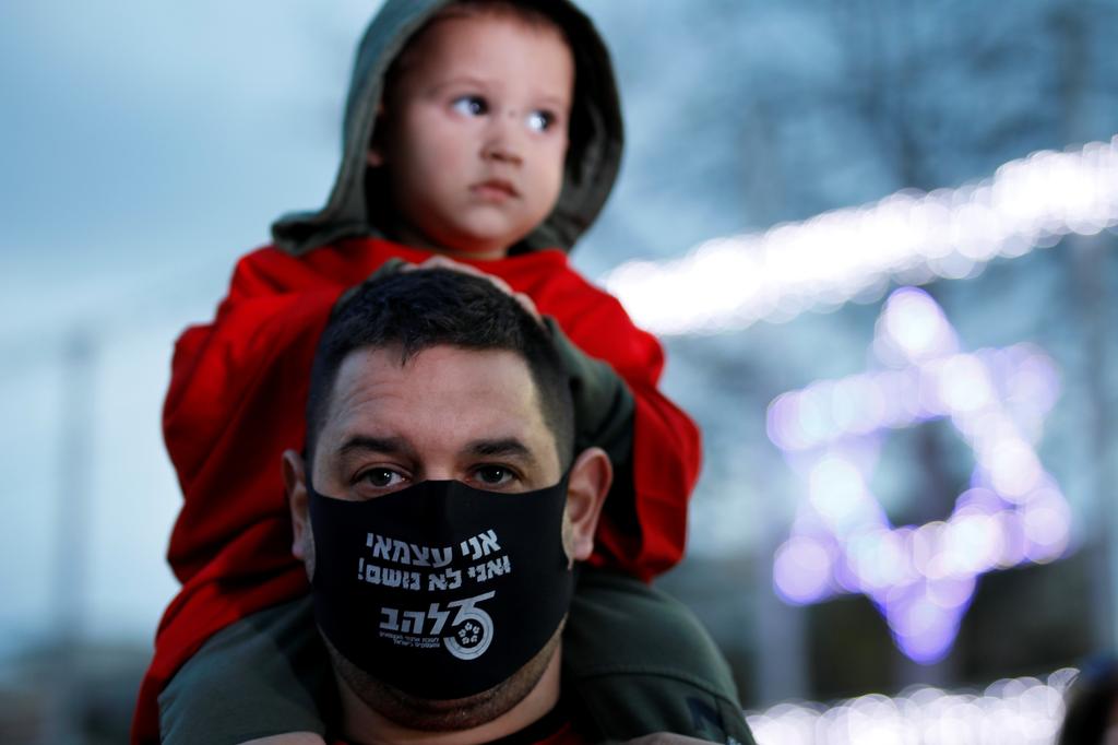 A man protests over the government handing of the coronavirus crisis in Tel Aviv's Rabin Square. The words on his face mask read: 'I am self-employed and I cannot breathe' 