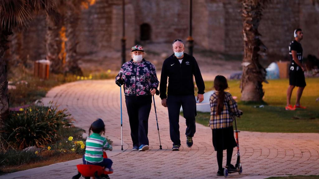 A couple wearing protective face masks while strolling through Ashkelon 