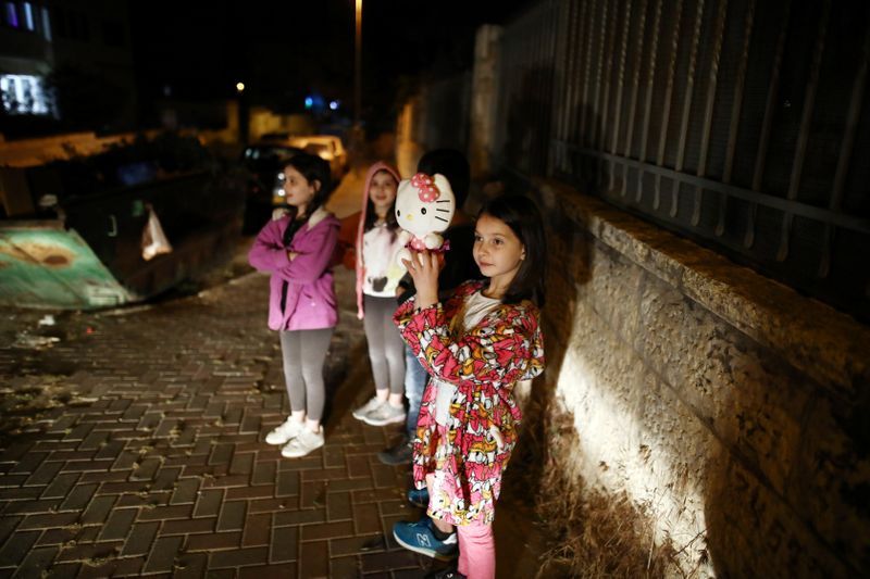 Children watch as a festive Ramadan float drives through a street in East Jerusalem 
