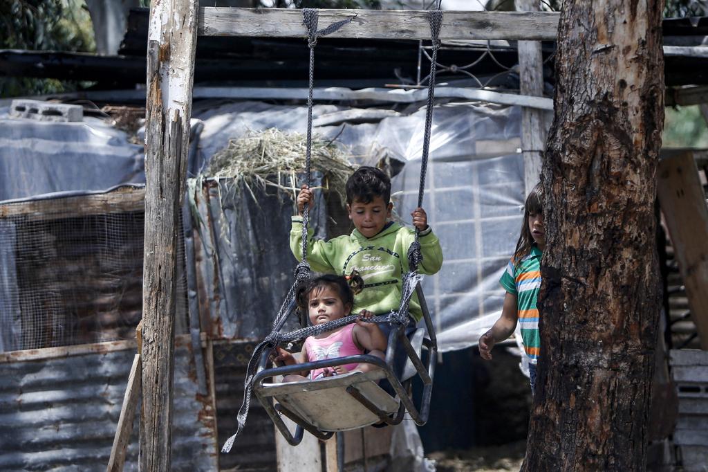Palestinian children ride on a swing near their home, east of Gaza City 