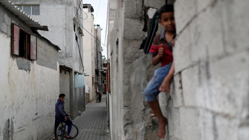 A Palestinian youth on a bicycle looks on as a boy sits on a wall in Jabalia refugee camp 