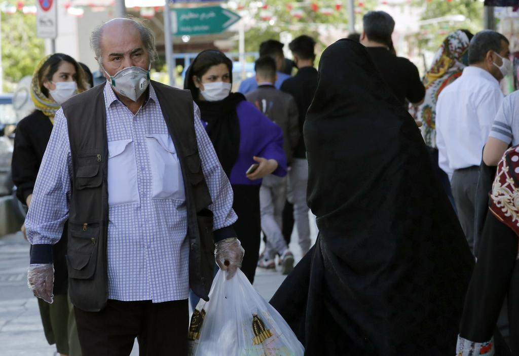 Iranians wearing face masks and protective gloves go shopping on a street in Tehran, May 7, 2020 