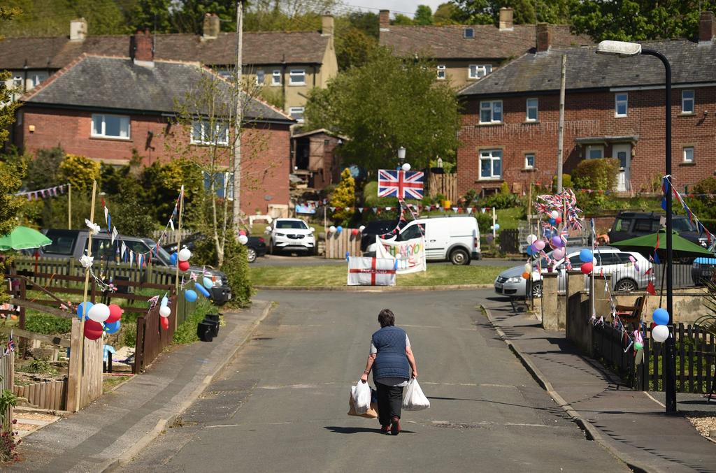 resident carries shopping bags as houses are decorated in bunting to mark the 75th anniversary of VE Day