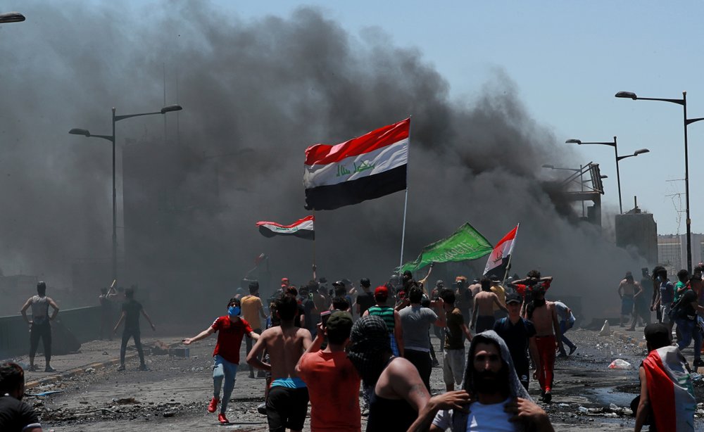 Anti-government protesters burn tires in front of barriers set up by security forces to close the Jumhuriyah Bridge leading to the Green Zone government area, during ongoing protests in Baghdad 